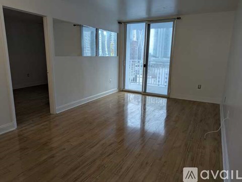 A room with wooden flooring and a sliding glass door leading to a balcony.