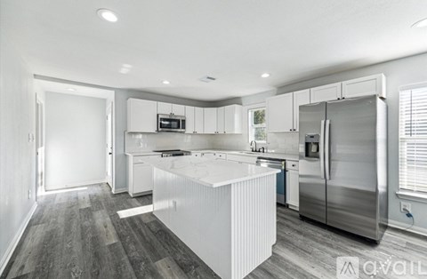 A modern kitchen with stainless steel appliances and white cabinetry.