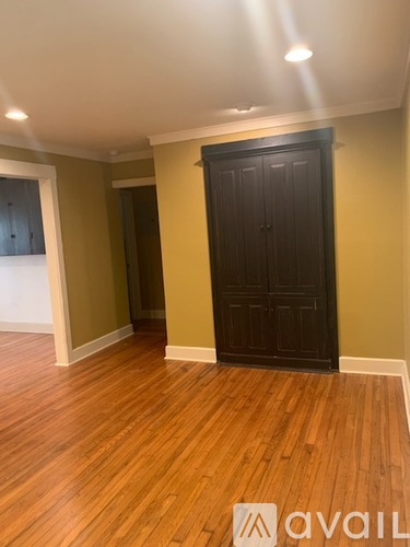 A room with a wooden floor and a dark brown door.