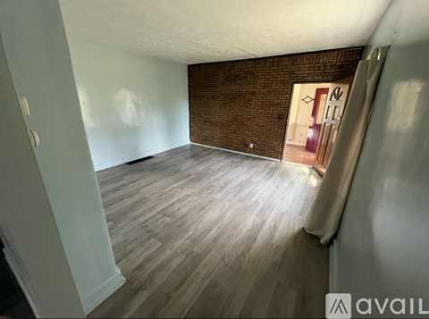 A room with wooden flooring and a brick wall.