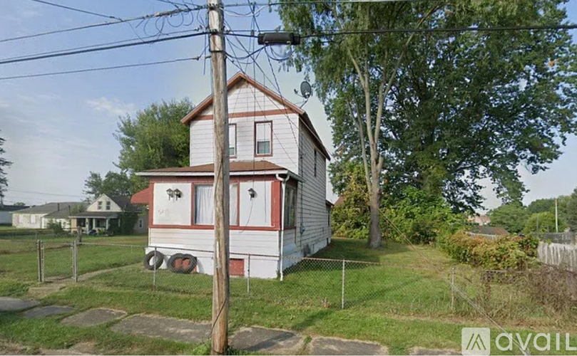 A two-story house with a red and white exterior is surrounded by a grassy yard.