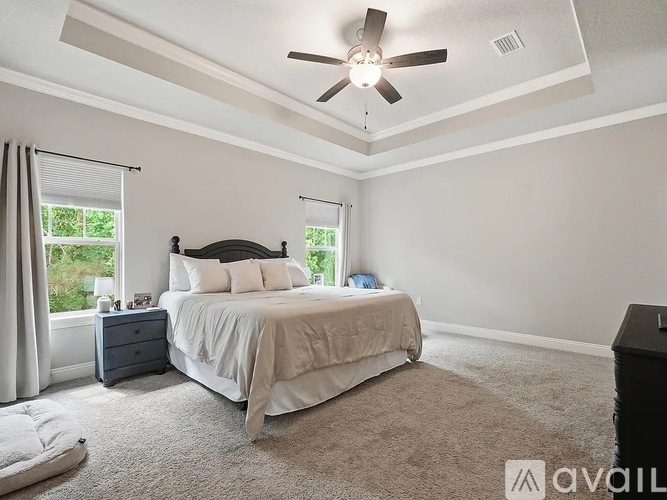 A bedroom with a large bed and a ceiling fan.