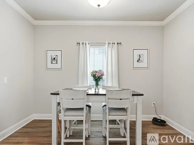 A dining room with a table set for two and a vase of flowers on the table.