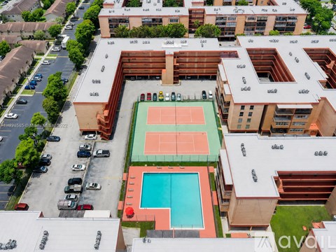An aerial view of a building with a tennis court and a pool.