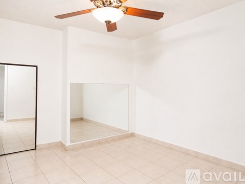 A room with a ceiling fan and a mirror on the wall.