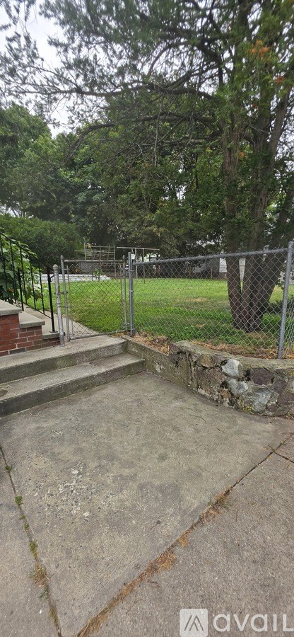 A concrete patio surrounded by a metal fence and trees.