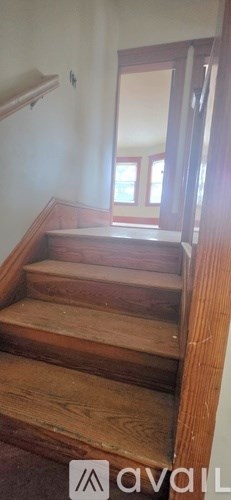 A wooden staircase with a white wall on the side.