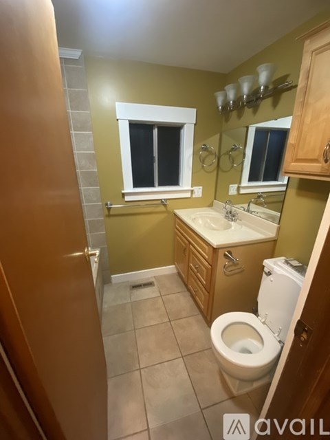 A bathroom with a toilet, sink, and mirror.