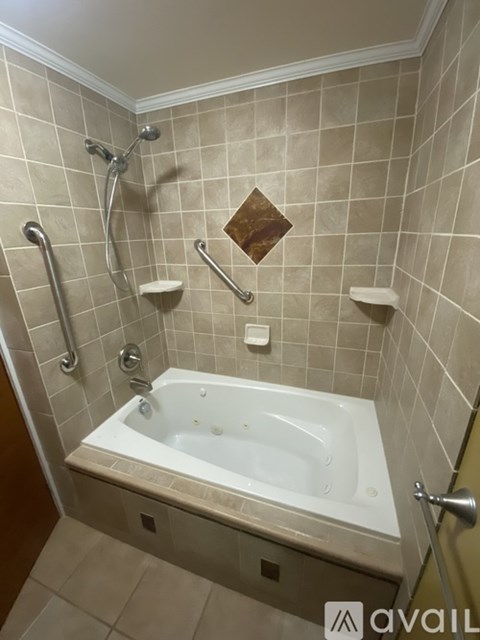 A bathroom with a white bathtub and a tile wall.