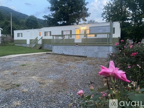 A white building with a balcony and a gravel area in front.