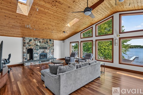 A living room with a grey couch and a stone fireplace.
