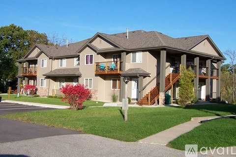 A large two-story house with a balcony and a red bush in front.