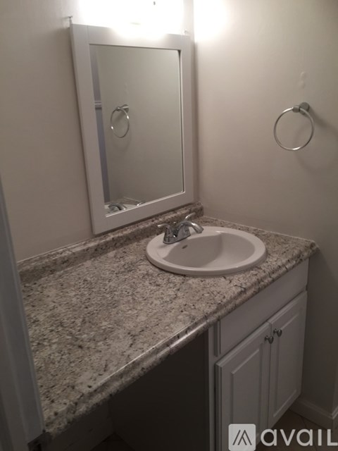 A bathroom sink with a granite counter top and a mirror above it.
