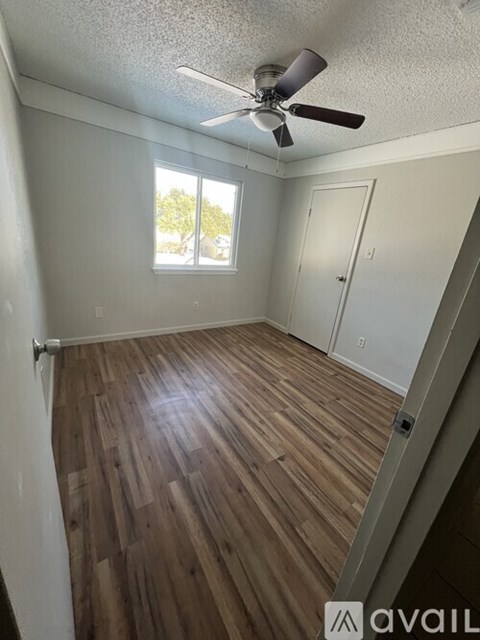 A room with a ceiling fan and wooden flooring.