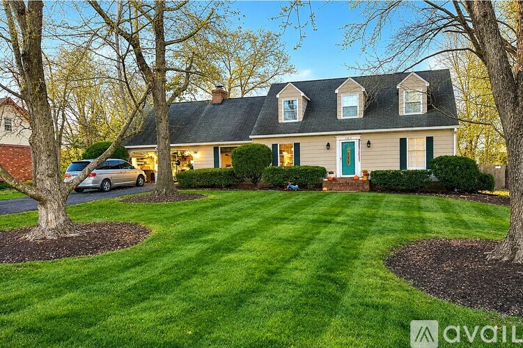 A house with a green door is surrounded by a well-manicured lawn.