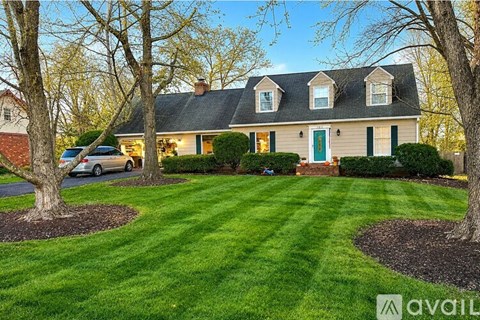 A house with a green door is surrounded by a well-manicured lawn.