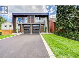 A modern house with a large driveway in front.