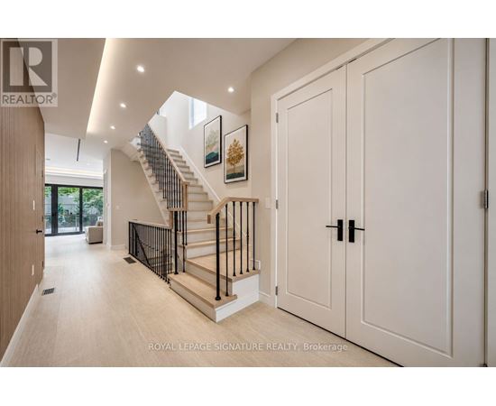 A spacious hallway with a staircase and white walls.