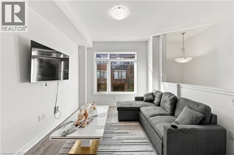 A modern living room with a grey sofa and a flat screen TV mounted on the wall.