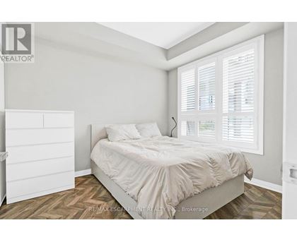 A bedroom with a bed, nightstand, and window with blinds.
