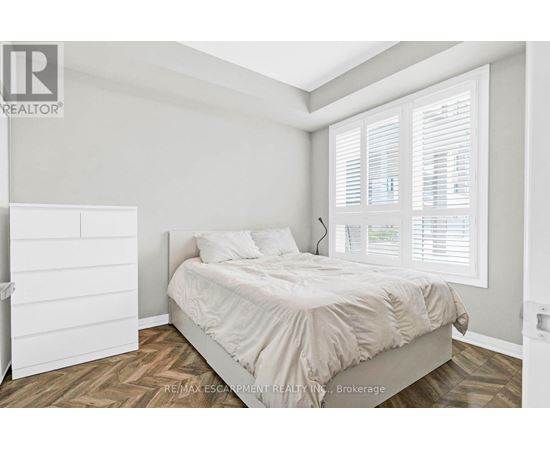 A bedroom with a bed, nightstand, and window with blinds.