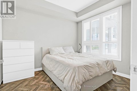 A bedroom with a bed, nightstand, and window with blinds.