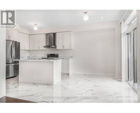 A white kitchen with a marble floor and a refrigerator on the left.
