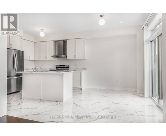 A white kitchen with a marble floor and a refrigerator on the left.