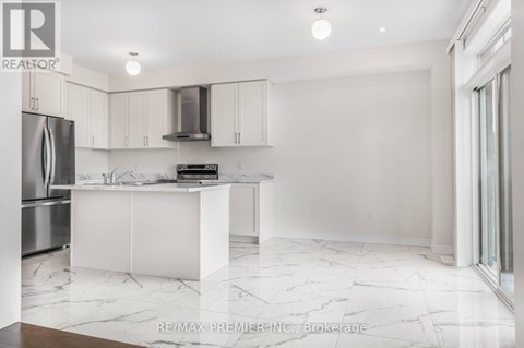 A white kitchen with a marble floor and a refrigerator on the left.