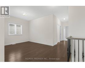 A room with wooden floors and white walls, with a window on the left side.