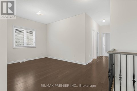 A room with wooden floors and white walls, with a window on the left side.