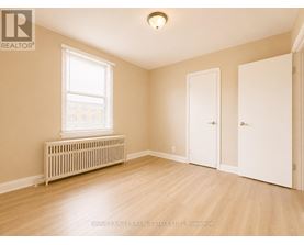 A room with a window, a radiator, and a wooden floor.