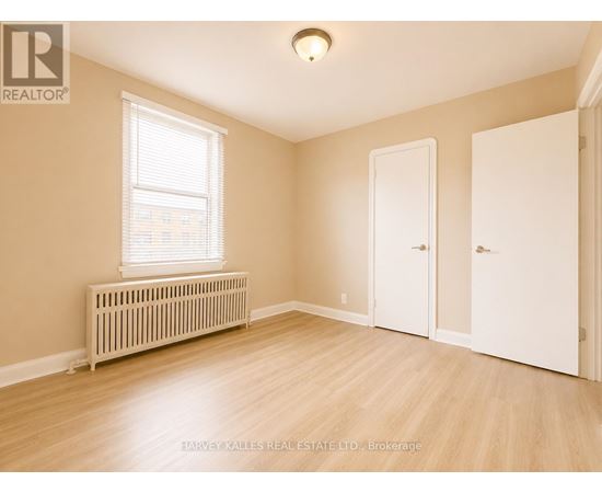 A room with a window, a radiator, and a wooden floor.