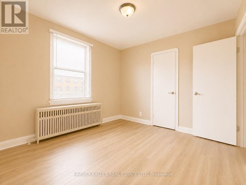 A room with a window, a radiator, and a wooden floor.
