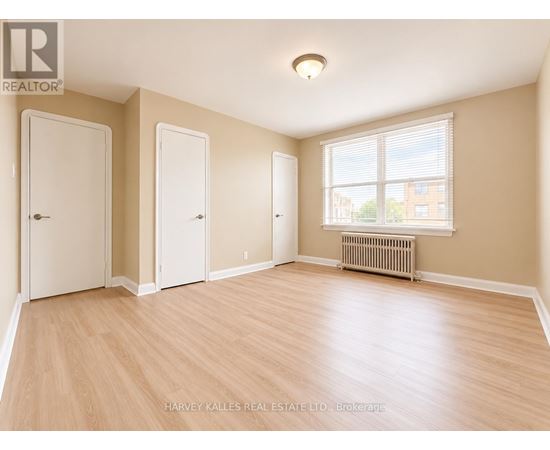 A room with wooden flooring and three doors.