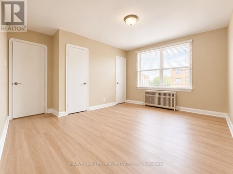 A room with wooden flooring and three doors.