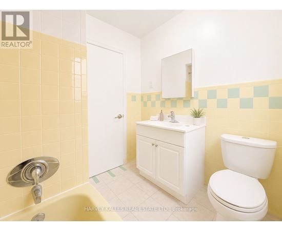 A bathroom with yellow tiles and a white toilet.