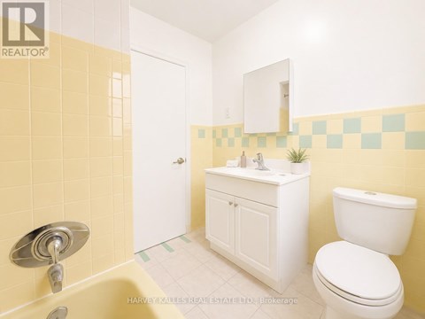 A bathroom with yellow tiles and a white toilet.