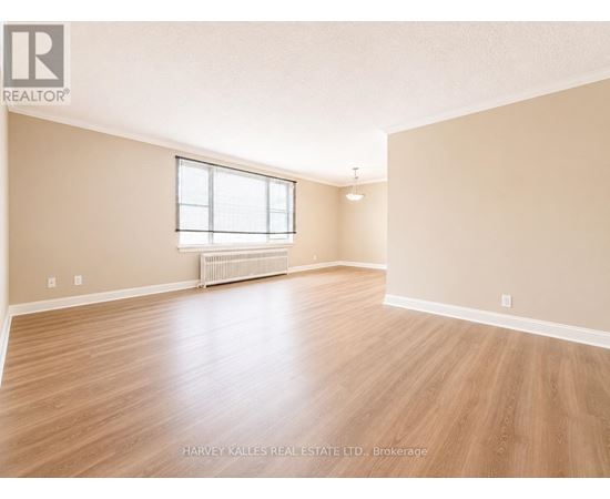 A spacious room with wooden flooring and a window.