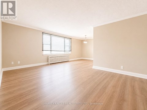 A spacious room with wooden flooring and a window.