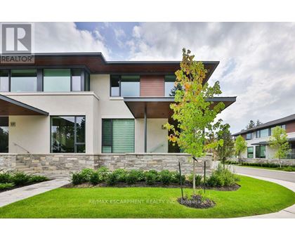 A modern house with a stone wall and a tree in front.