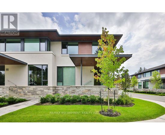 A modern house with a stone wall and a tree in front.