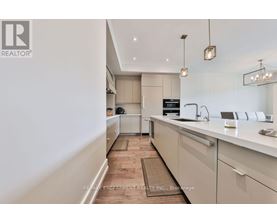 A modern kitchen with white cabinets and a wooden floor.