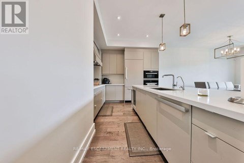 A modern kitchen with white cabinets and a wooden floor.