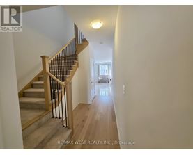 A hallway with a staircase and a light on the wall.