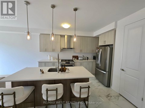 A kitchen with a table and chairs in the foreground and a refrigerator in the background.