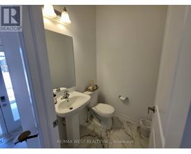 A white bathroom with a sink, toilet and mirror.