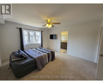 A bedroom with a bed, a ceiling fan, and a window with curtains.