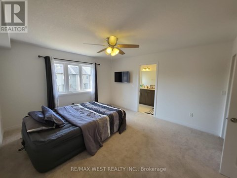 A bedroom with a bed, a ceiling fan, and a window with curtains.
