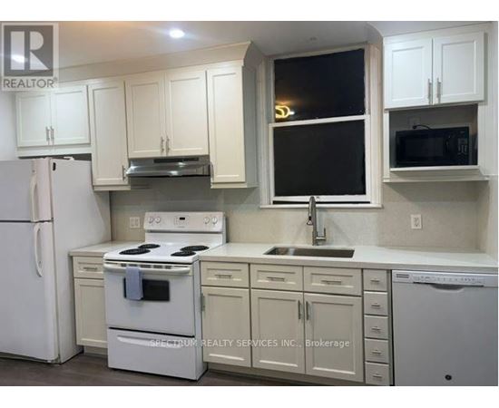 A white kitchen with a refrigerator, stove, and microwave.